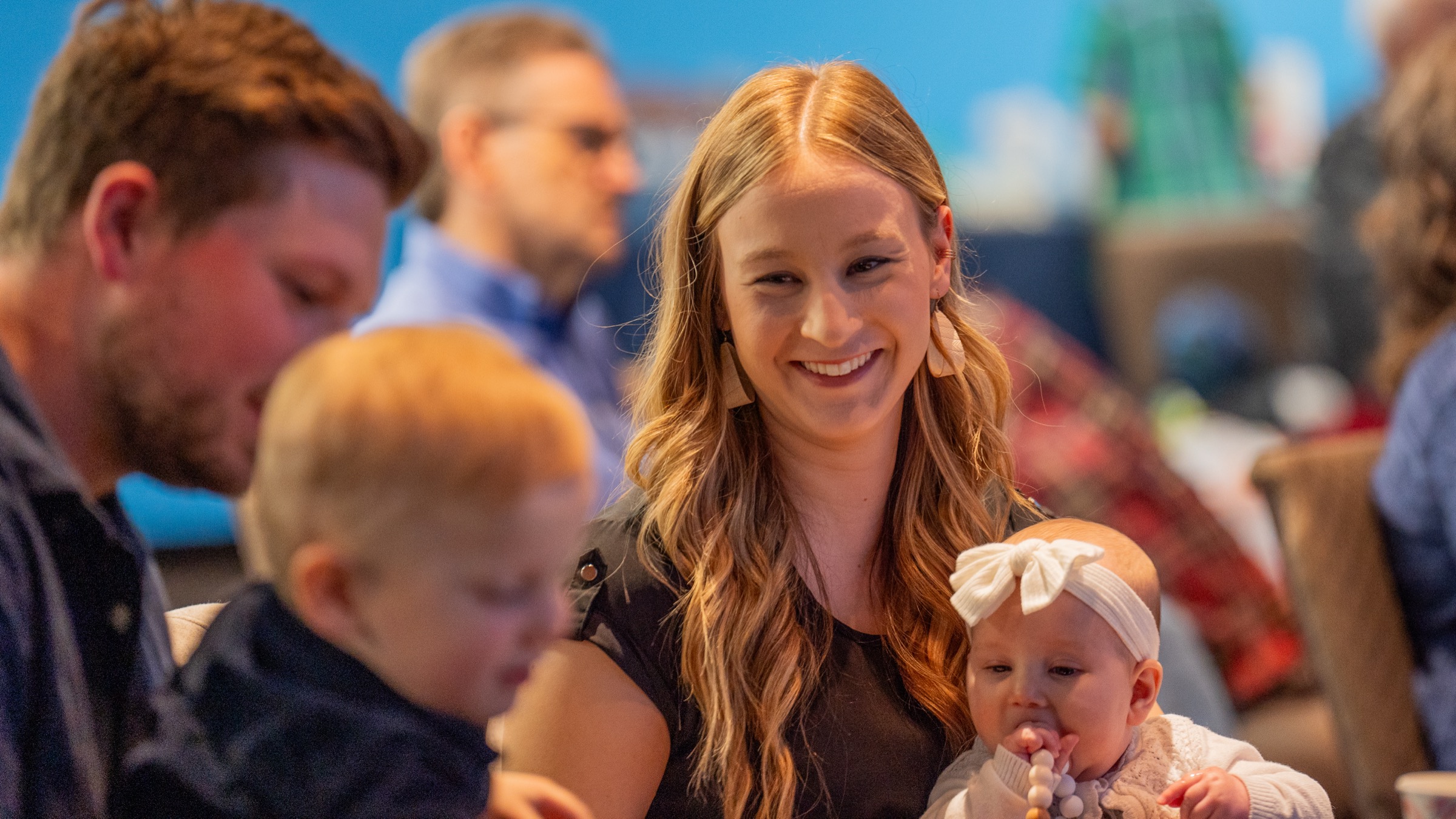 A mother smiling and holding her baby at a Parent Child Dedication