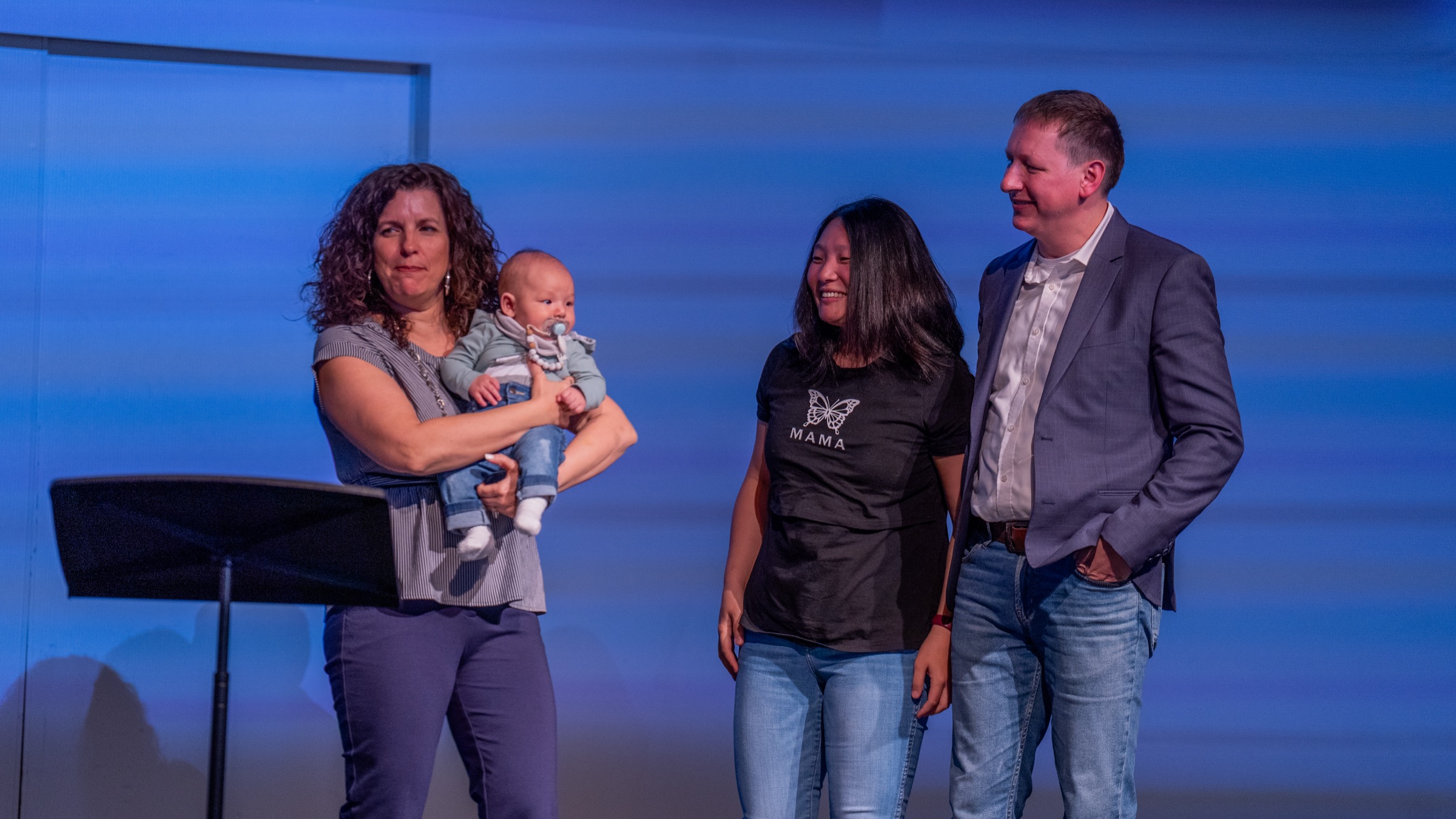 A family standing together on stage during a Parent Child Dedication