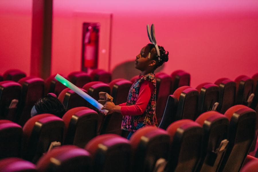 A girl with bunny ears and a glow stick in the auditorium at Easter Blast