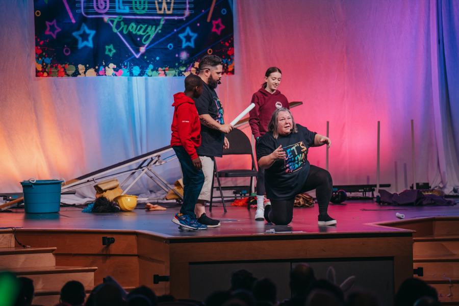 Leaders running a game on stage while kids watch at Easter Blast