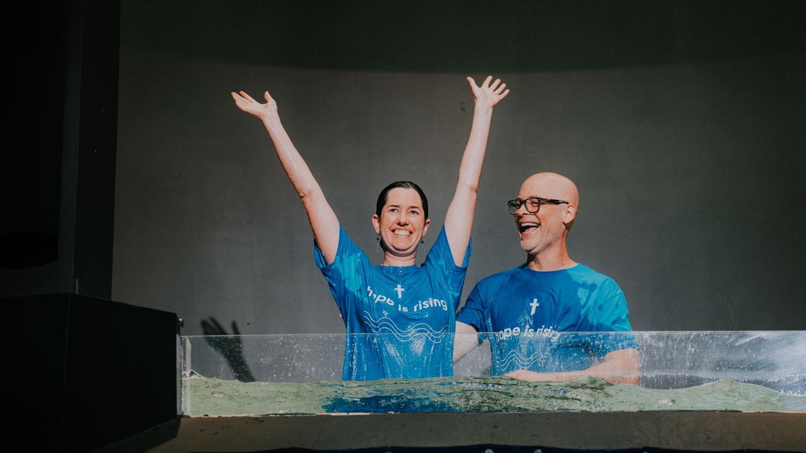 A woman celebrating with raised arms right after being baptized at Tidal Church