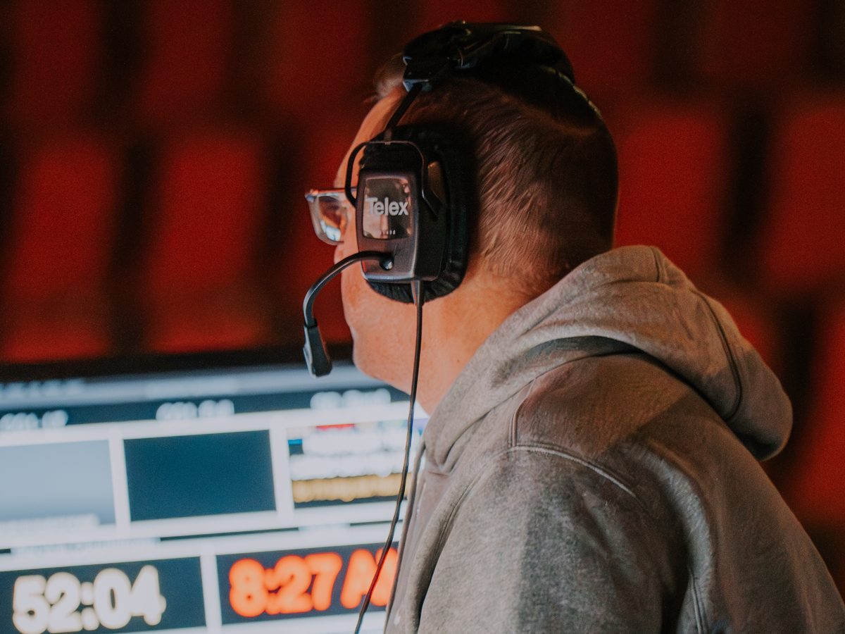 A production volunteer on headset running a Sunday service from the tech booth